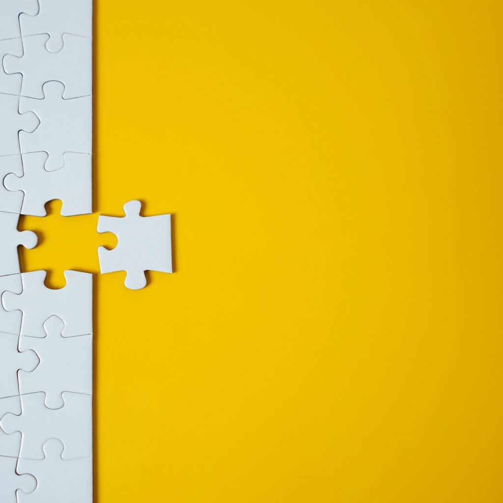 White jigsaw puzzle on yellow background. Team business success partnership or teamwork.