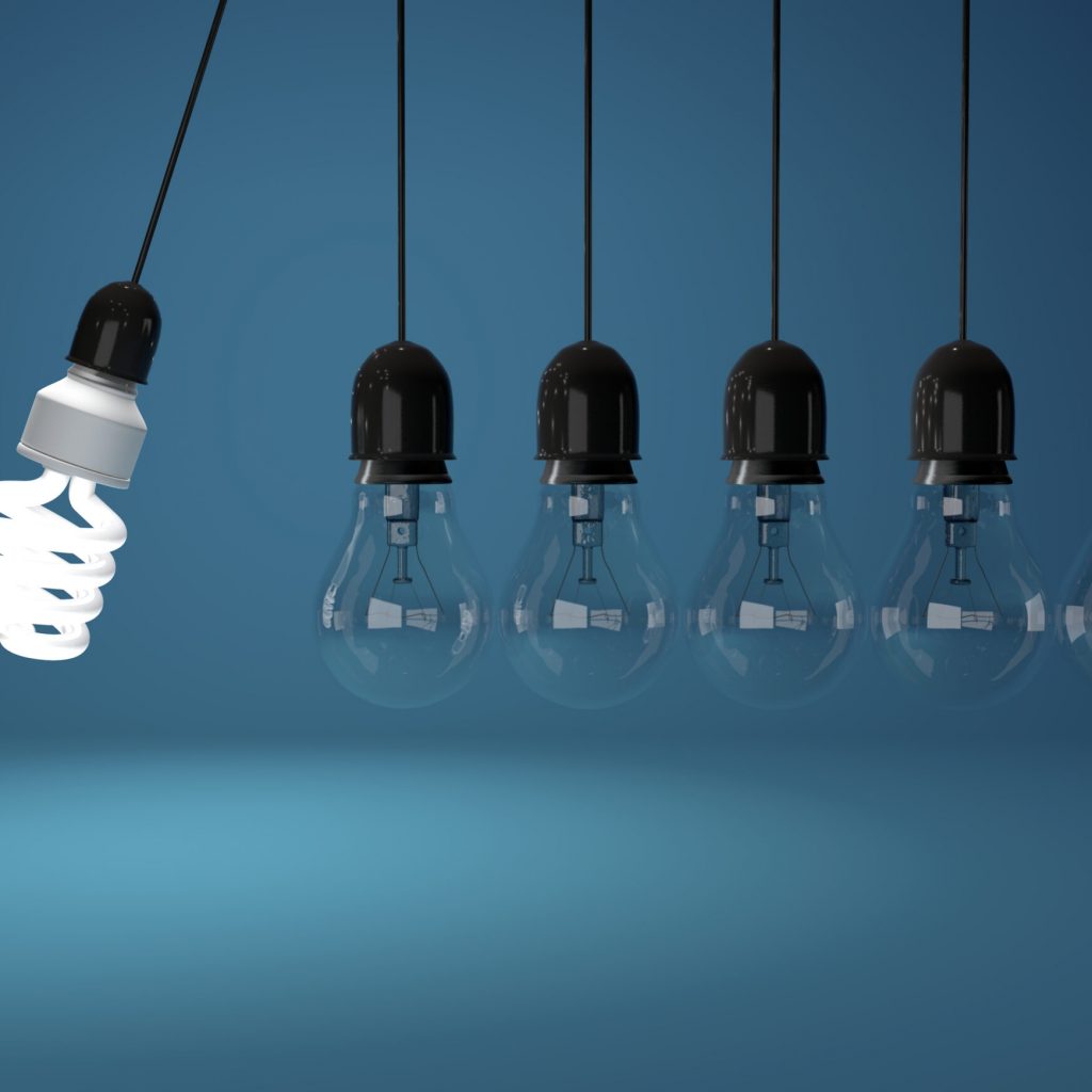 Energy saving bulb and incandescent bulb in perpetual motion over blue background