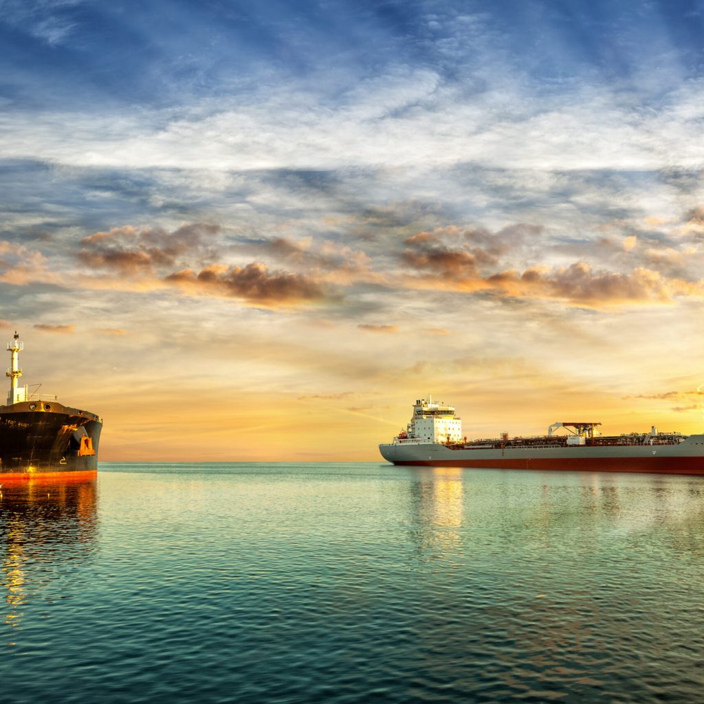 Two tanker ships on sea in the rays of the setting sun.