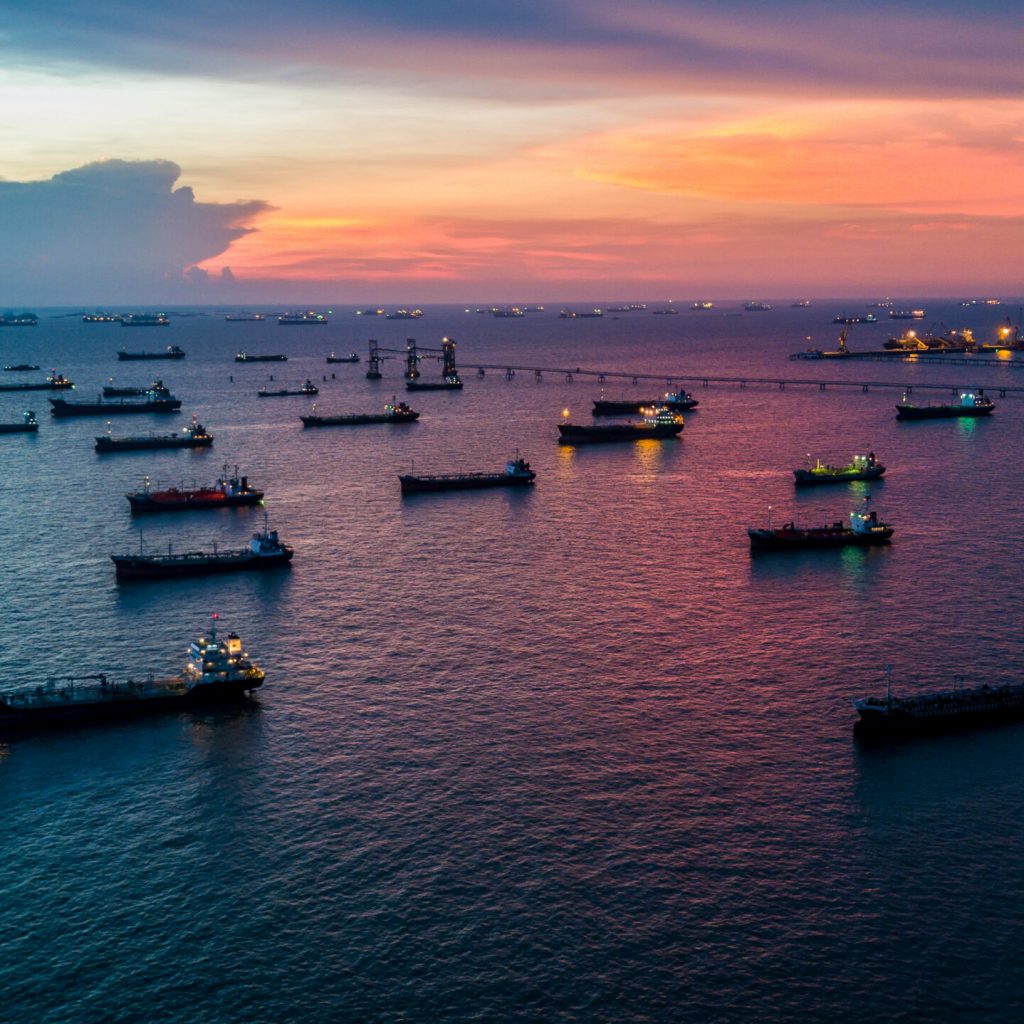Aerial view Crude oil tanker under cargo operations on typical shore station with clearly visible mechanical loading arms and pipeline infrastructure.